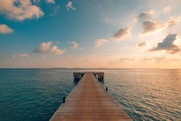 Beautiful seascape long jetty pier at sunset. Minimal sea sky, calm water surface and reflections. Colorful peaceful sunrise tones orange, gold, blue. Tranquil relaxing panoramic inspire meditation
