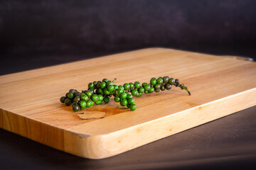 fresh green black pepper on a light wooden cutting board