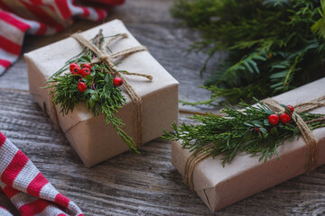 Christmas present decorated with branch of cotoneaster and green pine branch on wooden old background