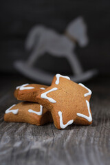 Christmas cookies in the shape of a star with white icing and white wooden horse on old wooden background. Vertical image.