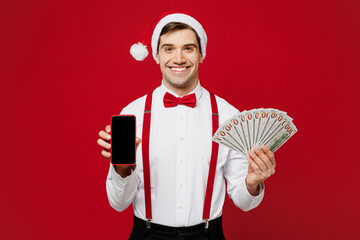 Merry young man wear white shirt Santa hat posing hold fan of cash money in dollar banknotes blank...