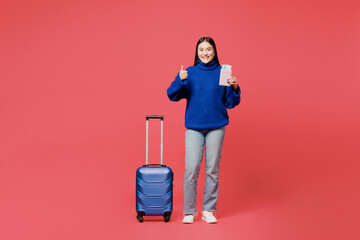 Traveler woman wearing blue sweater casual clothes hold suitcase point aside isolated on plain pink background Tourist travel abroad in free spare time rest getaway. Air flight trip journey concept