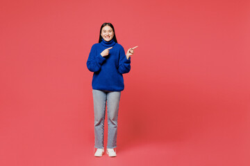 Full body young woman of Asian ethnicity wear blue sweater casual clothes point index finger aside on area mock up area copy space isolated on plain pastel pink background studio. Lifestyle concept.