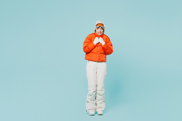 Full body freezing young skier woman wear padded windbreaker jacket hat ski goggles mask warm herself look aside travel rest spend weekend winter season in mountains isolated on plain blue background. © ViDi Studio