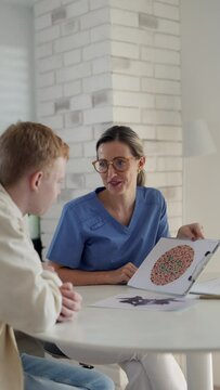 Ophthalmologist examining teenage boys's vision, doing Ishihara colour test. Doctor checking health of eyes and vision of teenage patient. Annual eye check up, ophthalmic exam for adolescents.