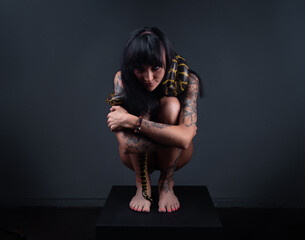 Photo of the brunette woman squatting with yellow anaconda