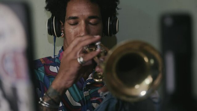 Inspired jazz musician playing trumpet recording song with microphone