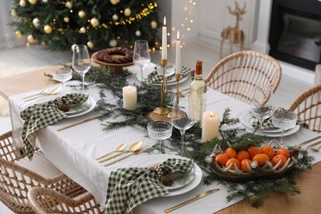 Christmas table setting with festive decor and dishware in room