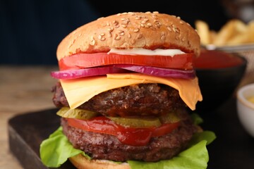 Tasty cheeseburger with patties and tomato on table, closeup