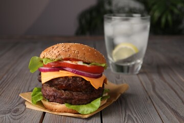 Tasty cheeseburger with patties and tomato on wooden table. Space for text