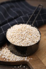 Raw barley groats in scoop on table, closeup