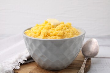 Tasty cornmeal with butter in bowl served on table, closeup