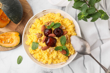 Tasty cornmeal with dates, nuts and mint in bowl served on white marble table, flat lay