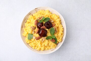 Tasty cornmeal with dates, nuts and mint in bowl on light table, top view