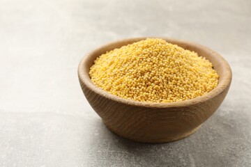 Millet groats in bowl on light grey table, space for text