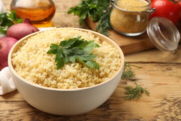 Delicious bulgur with parsley on wooden table, closeup