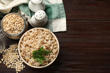 Delicious pearl barley with parsley served on wooden table, flat lay. space for text