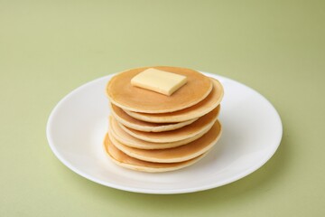 Delicious pancakes with butter on olive color background, closeup