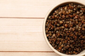 Delicious lentils in bowl on wooden table, top view. Space for text
