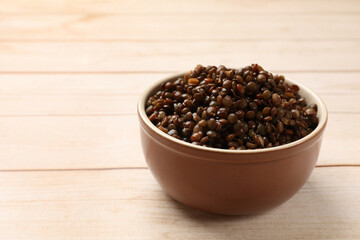 Delicious lentils in bowl on wooden table, closeup. Space for text