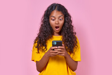 Young delighted beautiful Indian woman teen opens mouth in surprise reading message on mobile phone...
