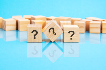 three question marks written on wooden cubes lying on the blue table, business and education...