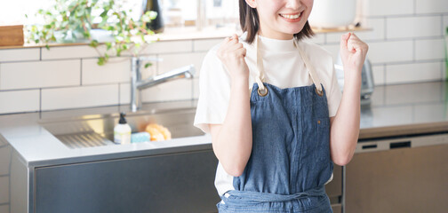 キッチンでガッツポーズする女性 © polkadot