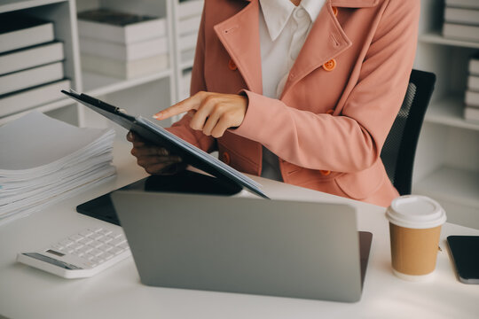 Attractive smiling young asian business woman work at home office, Asian woman working on laptop computer holding tablet.