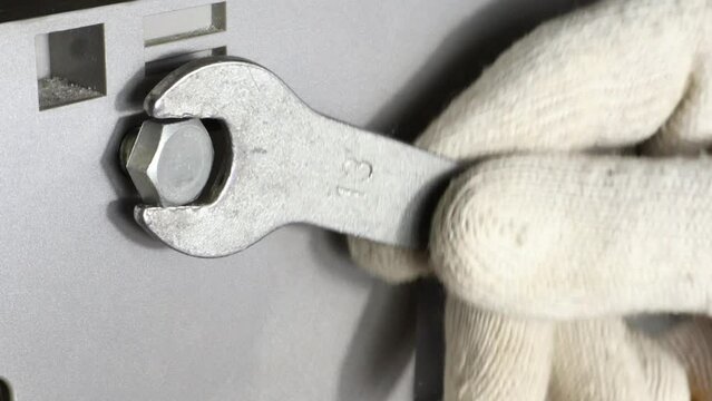 Tighten a nut with a wrench, machine part plastic background.