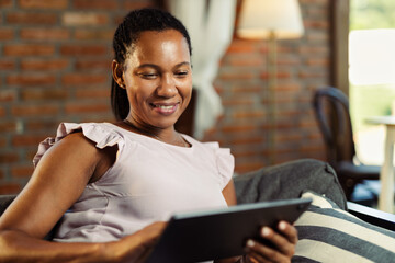 Happy black woman using digital tablet in the living room