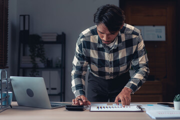 Businessman using calculator to checking financial and accounting report of business in office