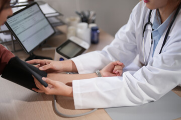 Asian psychologist women use sphygmomanometer with blood pressure cuff to checking blood pressure...