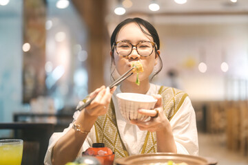 Happy asian woman holding rice bowl eating food at Japanese restaurant asia tasty from traditional...
