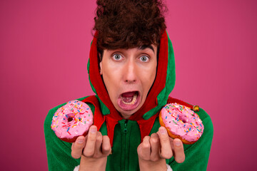 A funny guy in a New Year's costume is eating donuts. Sweet desserts and diet.