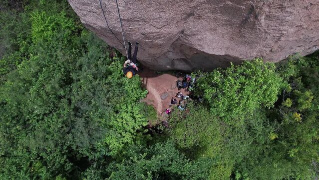 A young Indian girl is climbing or rappelling down the big rock amidst jungle