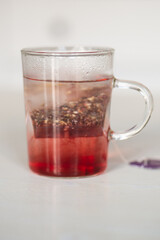 Tisane au cassis qui infuse dans une tasse transparente sur une table blanche