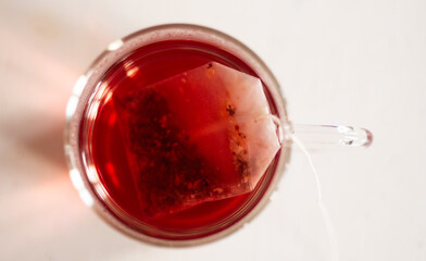 Tisane au cassis qui infuse dans une tasse transparente sur une table blanche