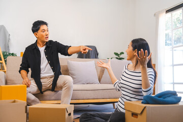 Asian couple during a stressful moment while moving, with the man gesturing widely and the woman looking upset and holding her head.