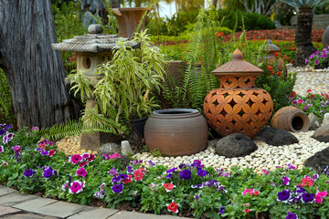 The eclectic garden decoration includes Japanese lanterns. Pottery jars of various shapes are...