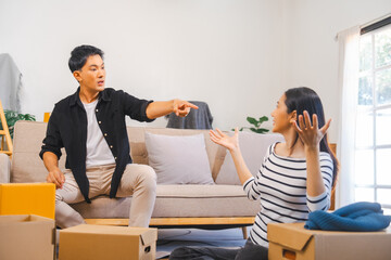 Asian couple during a stressful moment while moving, with the man gesturing widely and the woman...