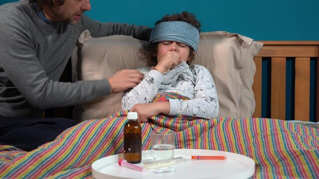 9 year old boy sick at home with fever -staying in bed at home with flu and taking antibiotic medicine to treat fever after experiencing fever with thermometer  Covid-19 Coronavirus epidemic in Child 