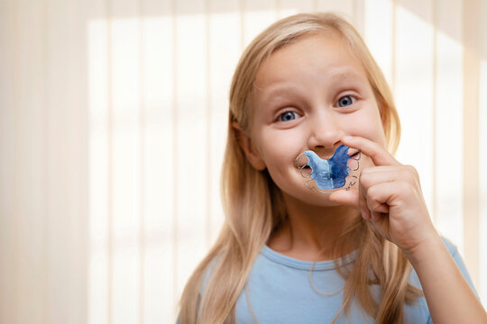 Retainer for Expansion Jaw of Children. Happy Child Little Girl holding Orthodontic Plate Teeth in Hands. Dental plate. Copy space.