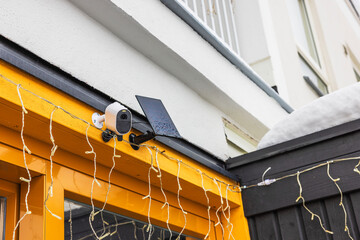 Close-up view of exterior surveillance camera equipped with solar panel installed on facade of...