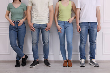 Group of people in stylish jeans near white wall indoors, closeup - Powered by Adobe