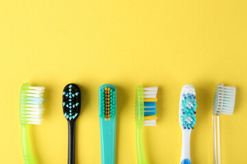Different toothbrushes on yellow background, flat lay. Space for text