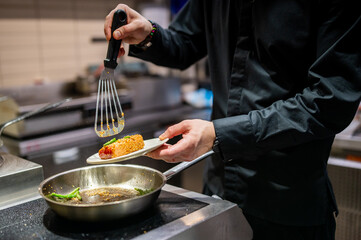 man chef cooking fried tuna fish in frying pan on kitchen