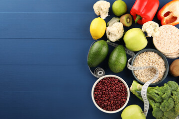 Healthy diet. Different products and measuring tape on blue wooden table, flat lay with space for text