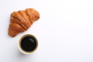 Delicious fresh croissant and paper cup of coffee on white background, flat lay. Space for text