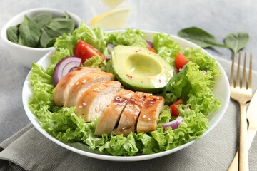 Delicious salad with chicken, avocado and vegetables served on table, closeup