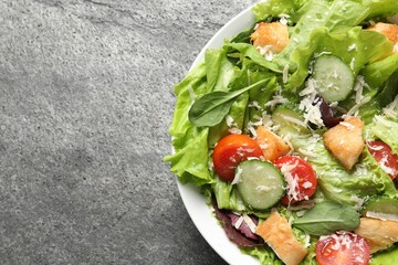 Delicious salad with chicken, cheese and vegetables on grey table, top view. Space for text